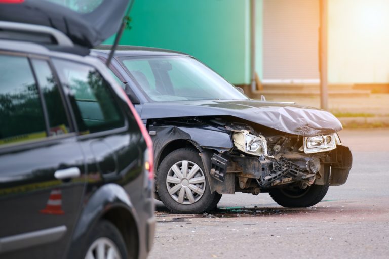 Damaged in car accident vehicle on city street crash site