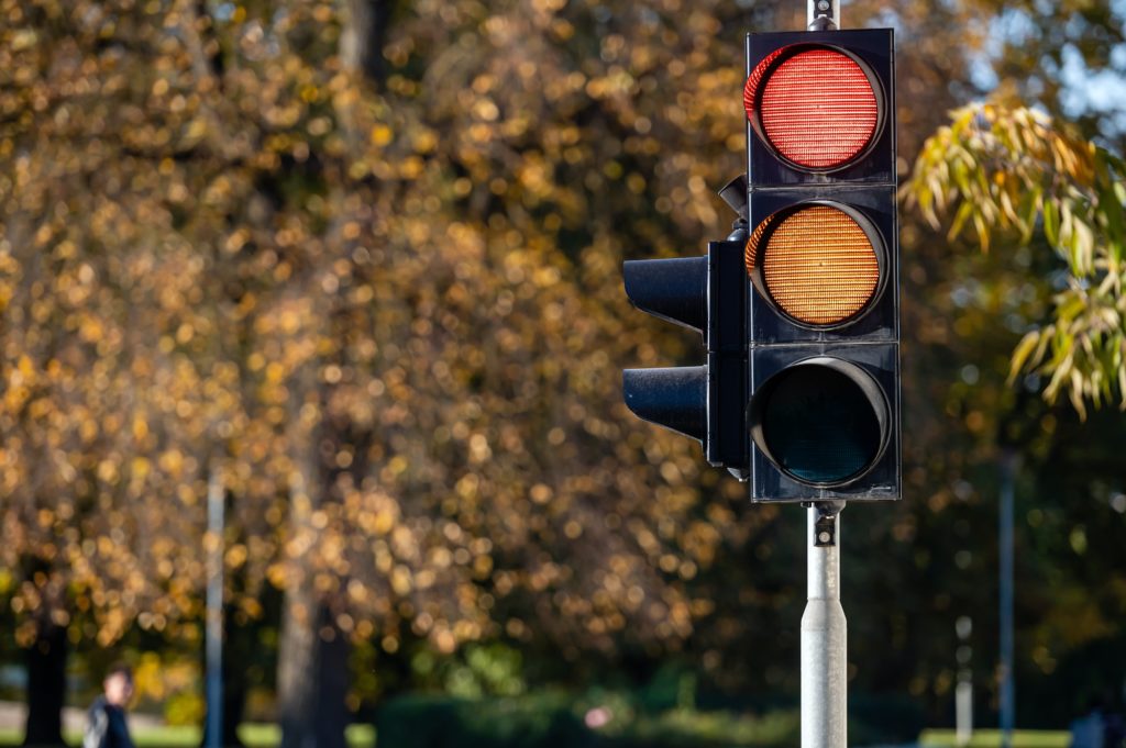 Red and orange traffic light in semaphore closeup. Bright colored autumn background.