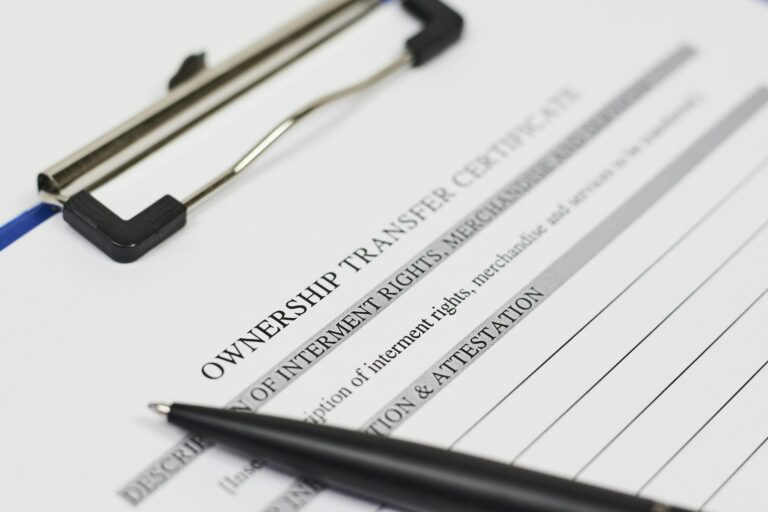 Soft focus of an ownership transfer certificate document on a clipboard with a pen