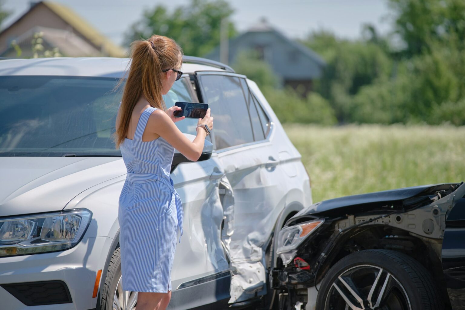 Stressed woman driver taking photo on mobile phone camera after vehicle collision