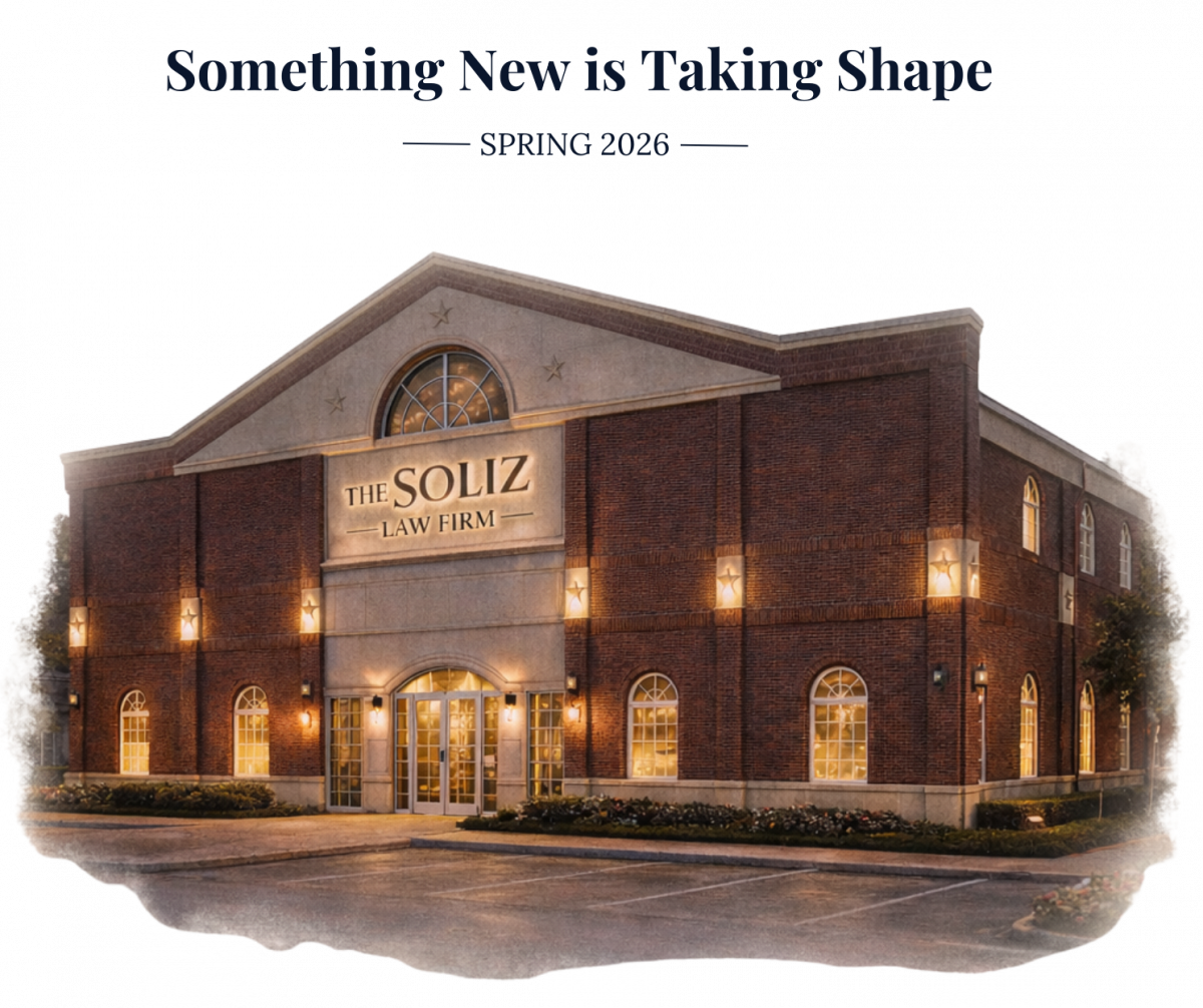 Teaser image of The Soliz Law Firm’s new office building, softly blended into a light cream background, showcasing a large red brick law office with warm interior lighting and refined architectural details, announcing a Spring 2026 opening.